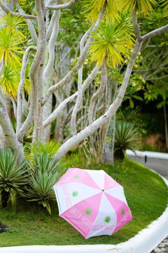 a pink umbrella sitting on the grass next to a tree at Raffy White Boracay in Boracay
