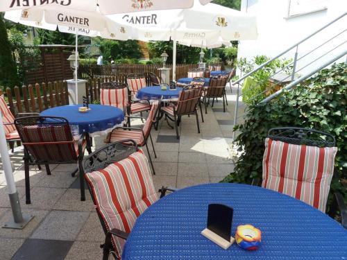 a patio with blue tables and chairs and umbrellas at Landgasthof-Hotel-Rössle in Oberprechtal