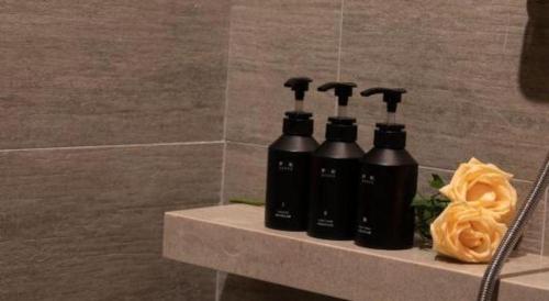 a group of four black bottles on a shelf in a bathroom at Atour Hotel Jinan Tangyan Century Avenue in Jinan