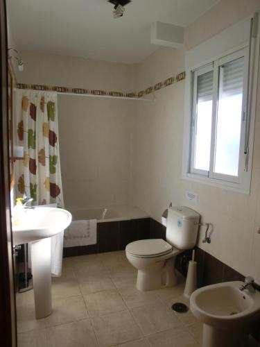 a bathroom with a toilet and a sink and a tub at Casa Quercus con piscina privada in Cortes de la Frontera