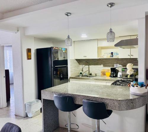 a kitchen with a counter and two blue stools at apartment in Condesa Caracol Acapulco in Acapulco