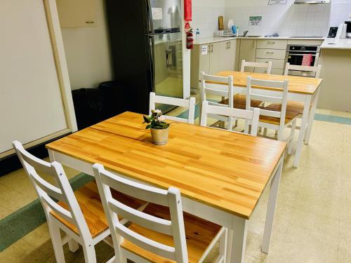 a kitchen with a wooden table and white chairs at Siesta Sydney in Sydney
