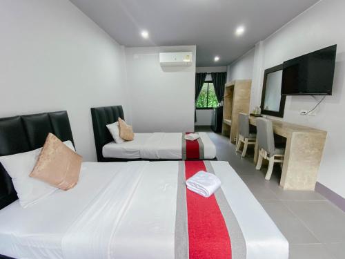 a bedroom with two beds and a flat screen tv at The Target Hotel chaingrai in Chiang Rai