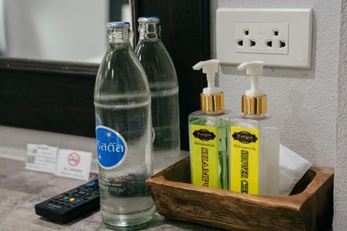 a bottle of water and two toothbrushes in a wooden box at The Target Hotel chaingrai in Chiang Rai