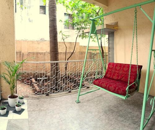 ein roter Stuhl auf einer Verandaschaukel in der Unterkunft Esha's Homely stay in Indāpur