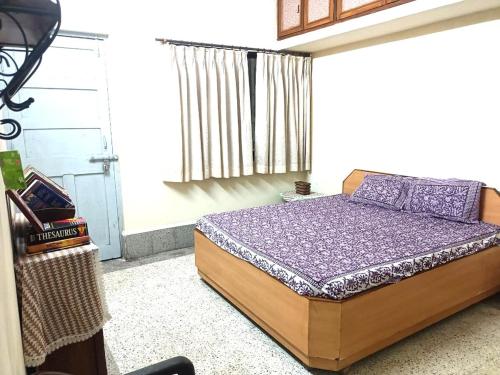 ein Schlafzimmer mit einem Bett mit violetter Bettwäsche und einem Fenster in der Unterkunft Esha's Homely stay in Indāpur