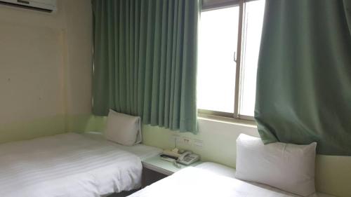 a hotel room with two beds and a window at Ryhan Hotel in Zhongli