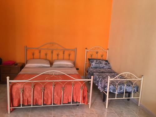 - une chambre avec 2 lits et un mur orange dans l'établissement Casa Luisa, à Portici