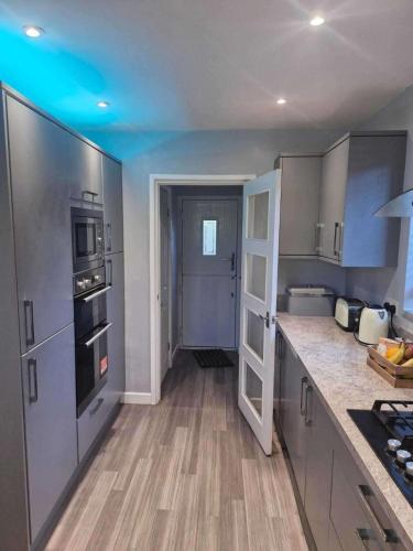 a kitchen with stainless steel appliances and wooden floors at 3Bedroom-Sleeps5-WiFi-SingleCarParking in Wythenshawe