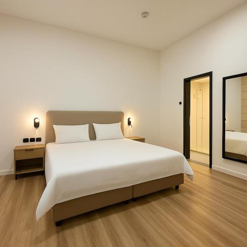a bedroom with a large white bed and a mirror at Hotel & Museum Dona Gracia in Tiberias