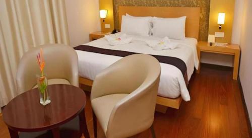 a hotel room with a bed and a table and chairs at The Axana Hotel in Padang