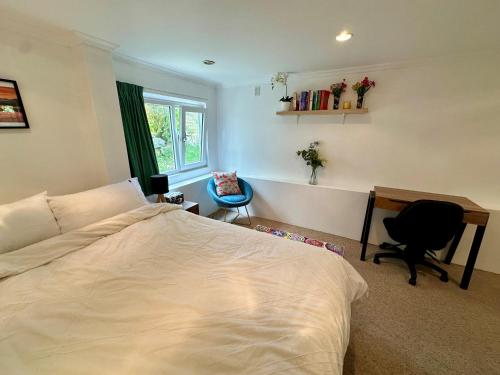 a bedroom with a bed and a desk and a chair at Cosy queen room with ensuite toilet and private bathroom, shared spa pool in Dunedin
