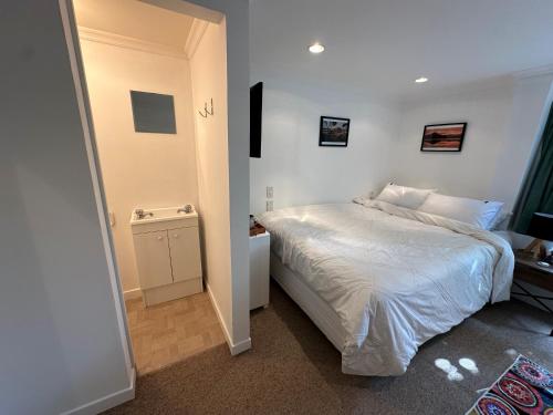 a bedroom with a white bed in a room at Cosy queen room with ensuite toilet and private bathroom, shared spa pool in Dunedin