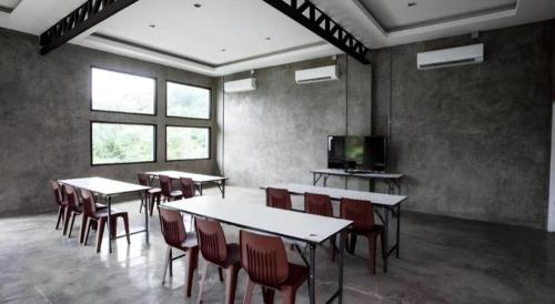a room with tables and chairs and a television at Ma-Kham Forest Resort in Nakhon Nayok
