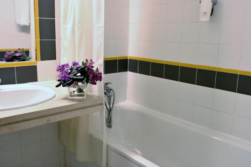 a bathroom with a sink and a bath tub with purple flowers at Flag Hotel Braga in Braga