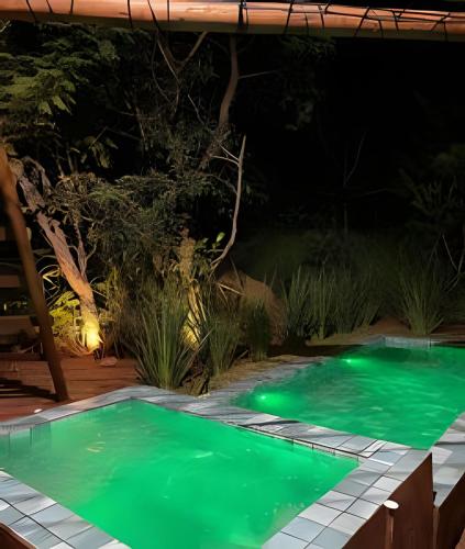 a swimming pool lit up at night with green lights at Espaço Gaia in Santana do Riacho