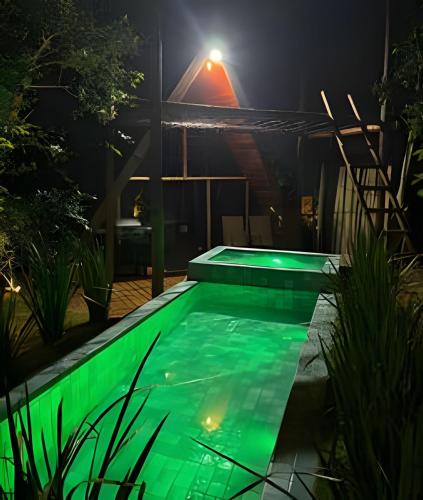 a swimming pool with green lighting at night at Espaço Gaia in Santana do Riacho