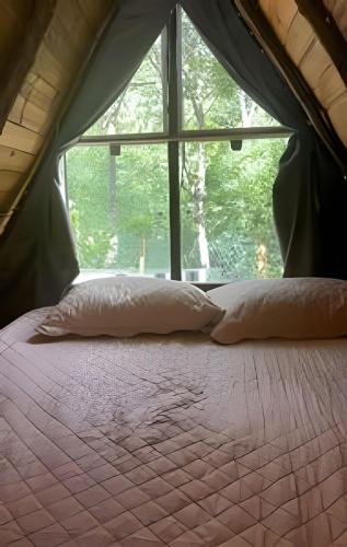 two pillows on a bed in a tent with a window at Espaço Gaia in Santana do Riacho