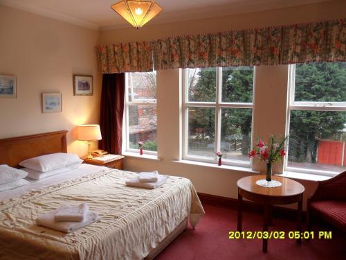 a bedroom with a bed and two windows at Thorpe Lodge Hotel in Peterborough