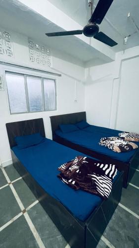 two beds in a room with blue sheets at Home Stay - Maa Kaamal Deep in Surat