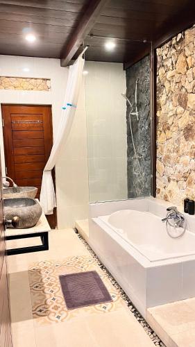 a bathroom with a bath tub and a sink at Villa Alcheringa Yogyakarta in Yogyakarta