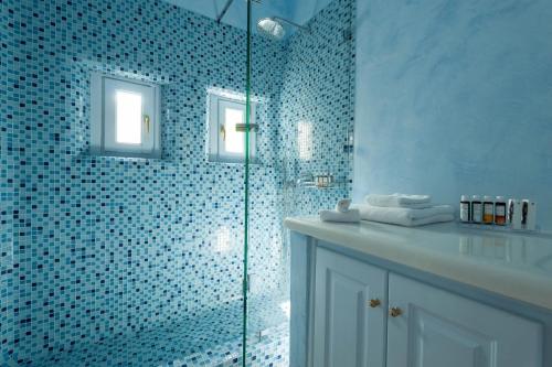 a bathroom with a glass shower with blue tiles at Aria Suites & Villas in Fira