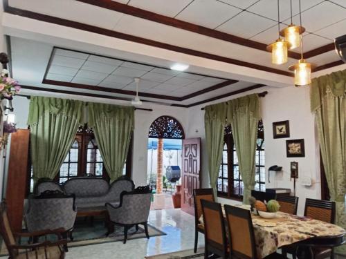 una sala da pranzo e un soggiorno con tende verdi di Spacious family holiday Home Near Airport, JAELA, Aussie holiday home a Ja-Ela