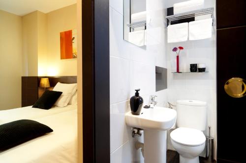 uma casa de banho com um lavatório, um WC e uma cama em THC Tirso Molina Hostel em Madri