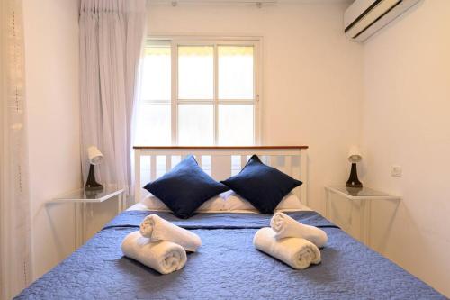 a bedroom with a bed with blue pillows and a window at העוגן והים - The Anchor and the Sea in Shlomi