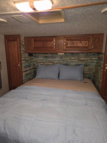 a bed in a small room with wooden cabinets at Fifth wheel in Kelso