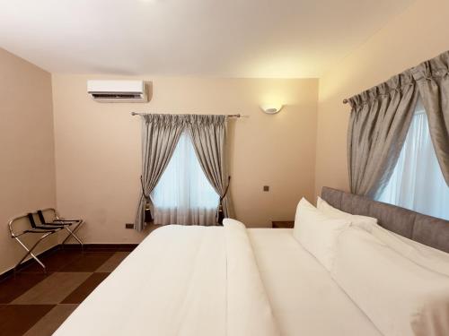 a bedroom with a large white bed and two windows at Hayat Apartments & Homes in Lagos