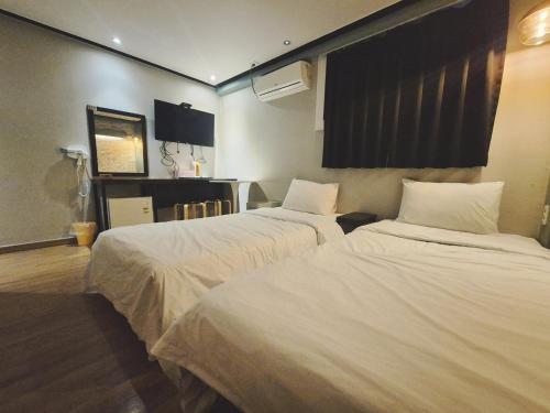 a hotel room with two beds with white sheets at 안온호스텔 성수건대 in Seoul