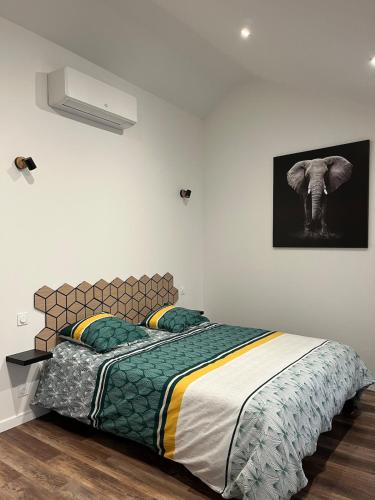 a bedroom with a bed and a picture of an elephant at LE ROUJOU Charmante maison tout confort au calme in Le Puy-Notre-Dame