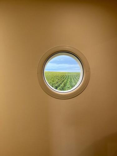 a round window in a room with a green field at LE ROUJOU Charmante maison tout confort au calme in Le Puy-Notre-Dame