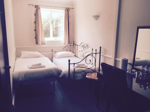 um pequeno quarto com 2 camas e uma janela em Leeford Place Hotel em Battle