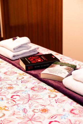 two books sitting on top of a bed with towels at Apartamento Plaza Perillana in Ponteareas