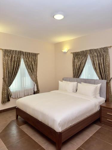 a bedroom with a large bed and two windows at Hayat Apartments & Homes in Lagos