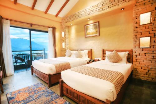 two beds in a hotel room with a balcony at Bar Peepal Resort in Pokhara