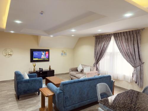 a living room with two blue couches and a tv at Hayat Apartments & Homes in Lagos