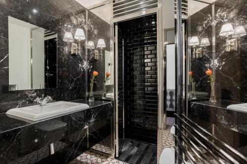 Baño negro con lavabo y espejo en Room Mate Anna, en Barcelona