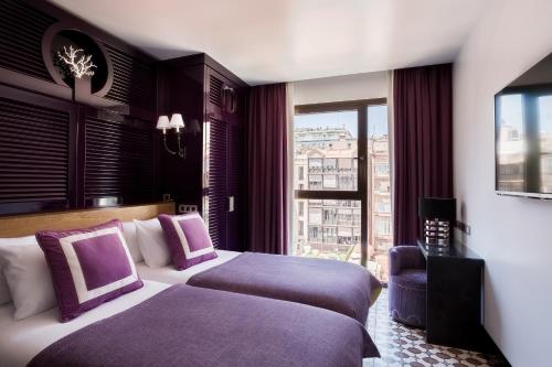 a hotel room with two beds and a window at Room Mate Anna, Barcelona in Barcelona