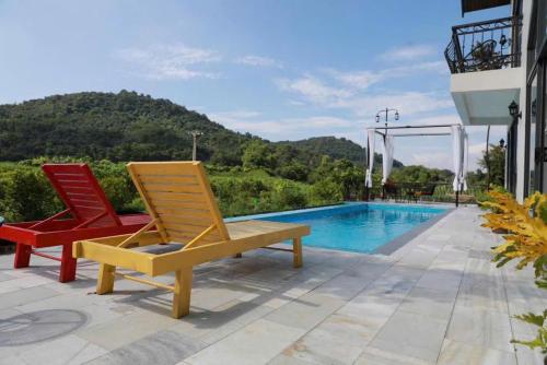 two lawn chairs sitting next to a swimming pool at Le Soleil Ba Vì in Ba Vì
