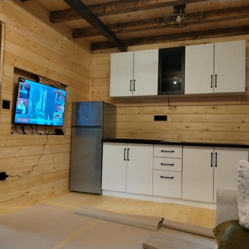 a kitchen with white cabinets and a flat screen tv at Brvnara Iva in Kolašin