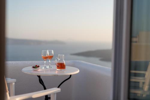 two glasses of wine sitting on a table on a balcony at Aria Suites & Villas in Fira