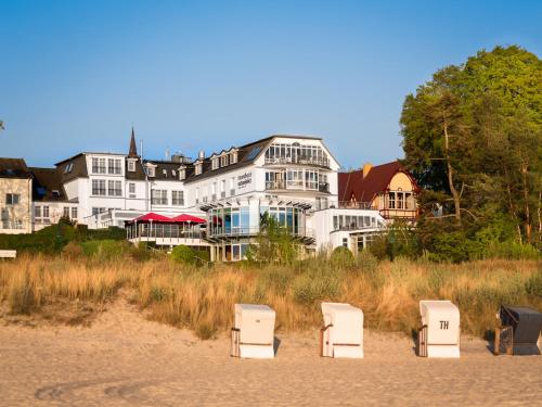 three chairs on the beach in front of a building at Strandhotel Ostseeblick in Heringsdorf