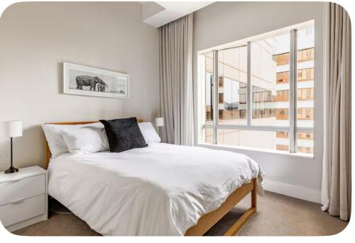 a bedroom with a bed and a large window at The Cozy Luxe Apartment in Cape Town