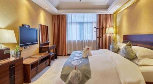 a hotel room with a large bed and a flat screen tv at Huangshan International Hotel in Huangshan