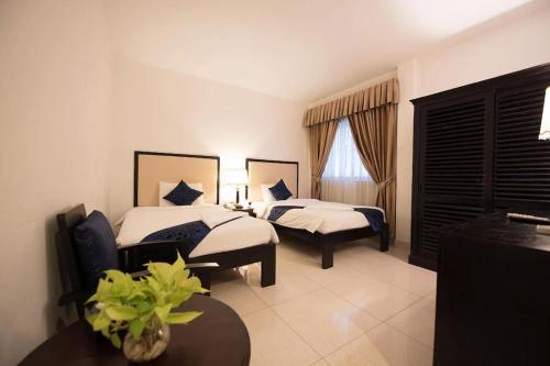 a hotel room with two beds and a table at Milan Hotel & Restaurant in Phnom Penh
