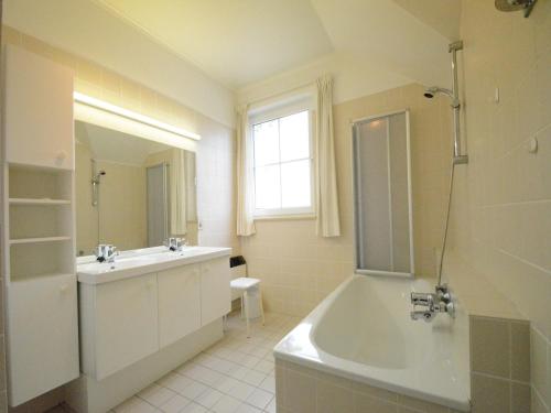 a white bathroom with a tub and a sink at Spacious villa near Lesse in Daverdisse