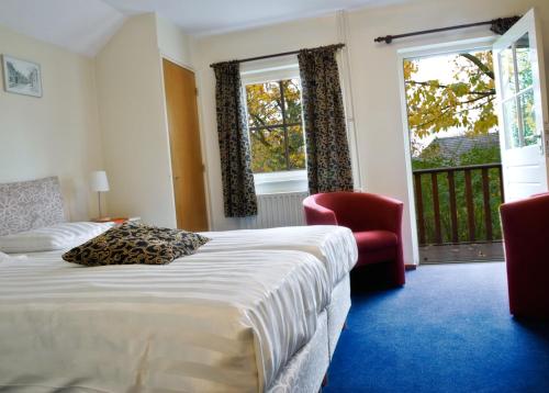 een hotelkamer met een bed, een stoel en ramen bij Hotel De Oude Brouwerij in Mechelen